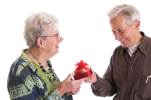 Senior couple celebrating valentines day together; with the man giving his wife a box of heart shaped chocolates