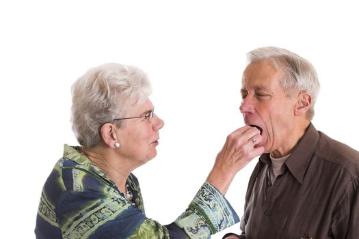 Elderly couple having fun; the woman is putting a chocolate in her husbands mouth