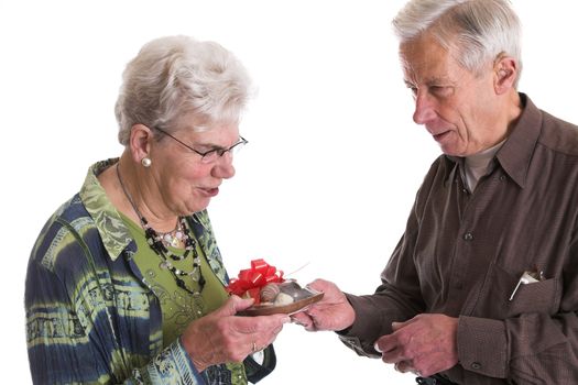 Elderly man giving his wife a chocolate heart filled with more chocolates for valentines day