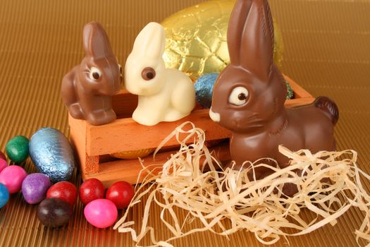 Various colors and shaped easter eggs and bunnies on a gold background