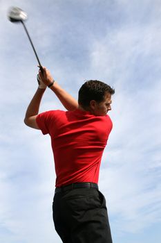 Young golfer with a driver against a blue clouded sky