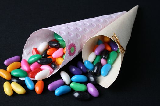 Cones filled with colorful jelly beans on a black background