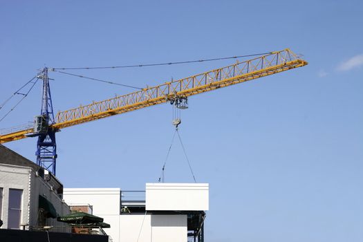 large crane lowering a large slab of concrete onto the side of a building construction