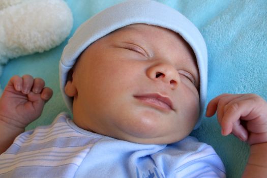 Week old baby boy on a blue blanket early in the morning