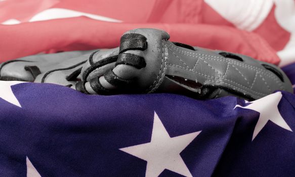 An old baseball glove in black and white and an American Flag.