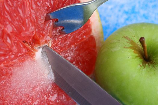 Sliced Pomelo with Sugar and a knife, fork and apple