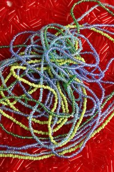 Strings of blue and green beads ontop of red beads