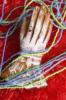 Ornate wooden hand on a bed of beads with strings