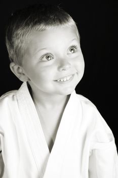 Young boy wearing his karate uniform on a black background 