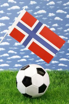 Soccerball on grass with norwegian national flag over sky background