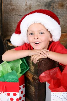 Young boy sitting inside an antique trunk wearing a christmas hat 