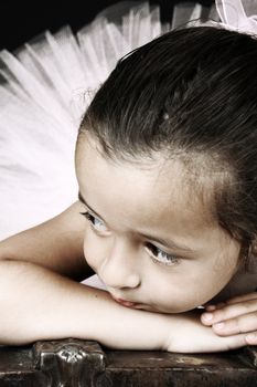 Cute little ballet girl wearing a tutu lying on an antique trunk