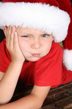 Bored little boy wearing a fluffy Christmas hat