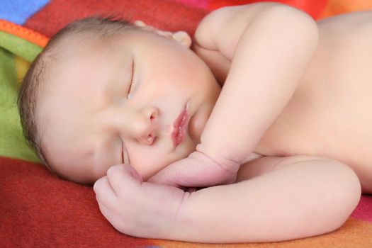 Newborn baby boy lying on a colorful blanket 