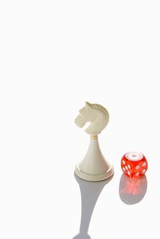 red dice and white chess knight on white background