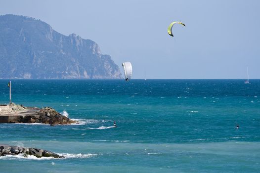 windy day on mediterranean sea: two man are enjoying surfing the waves. 