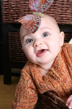 Six month old baby sitting infront of wooden drawers