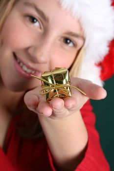 Teenager in red holding a golden gift in her hand. FOCUS ON GIFT