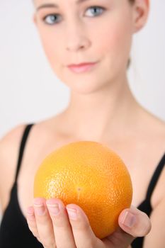Gym girl holding orange.  FOCUS ON ORANGE
