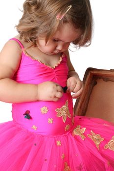 Little girl with wearing a bright pink tutu standing in an old suitcase
