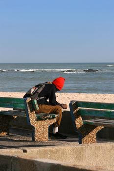 Lonely man sitting on a bench near the sea