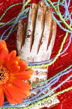 Wooden hand with beads and an orange flower