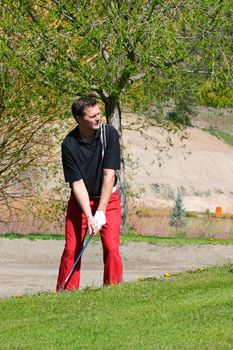 Young male golfer preparing to play a shot from the bunker