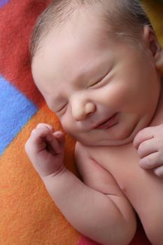 Newborn baby boy lying on a colorful blanket