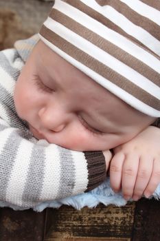 Beautiful baby boy sleeping in an antique trunk