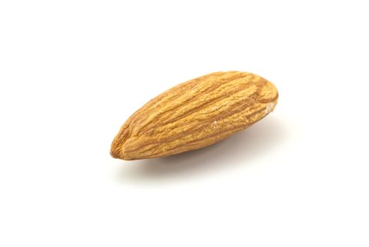 Close up of a solitary shelled almond, isolated on white surface with visible shadow.