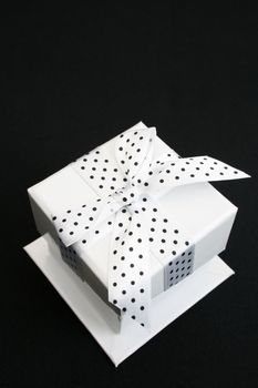 Small white box with a black and white spotted ribbon