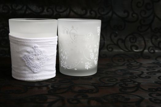 Two white glass holders with candles in