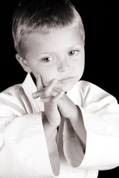 Young boy wearing his karate uniform on a black background
