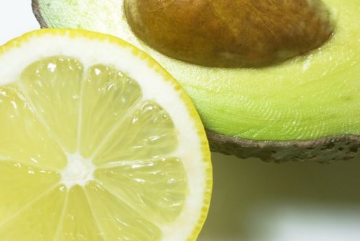 Close up shot of avocado (with stone) and lemon slice. 
