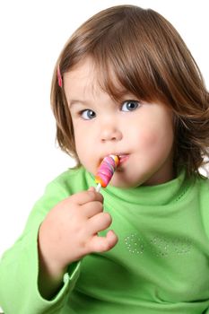 Toddler girl with chubby cheeks eating a sticky lollipop