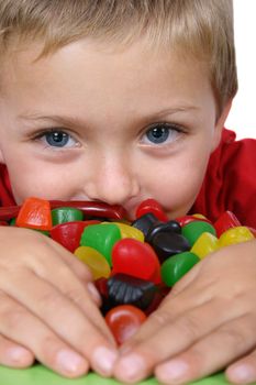 Young boy being with a table full of colorful sweets 