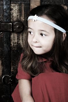 Cute brunette girl sitting against an antique trunk wearing a headband