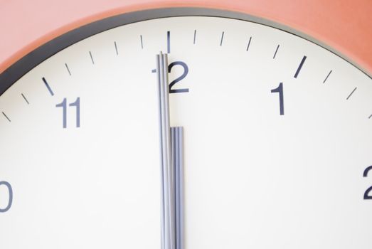 Clock with hands at 12am, midnight.  No visible background.  Cream face with black markings and sans serif typeface.  Grey hands.  Terracotta frame.