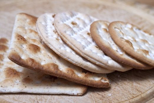 Closeup of crackers leaning against eachother on an old wooden chopping board.  Cut-marks visible.