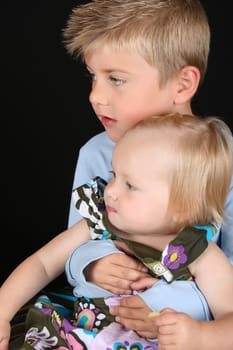 Cute brother holding his toddler sister in his arms 