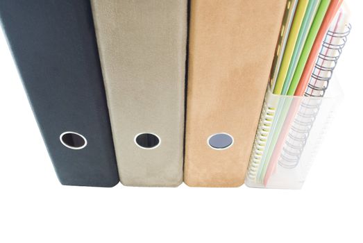 A row of folders and files, lever arch ring binders in suedette fabric - colours: black, tan and faun; a magazine rack in clear plastic containing slim cardboard files, colours: blue; green; orange; yellow; white together with a spiral bound notebook.  The subject matter has been extracted from the background - which is pure white.