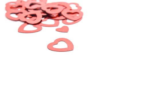 Decorative red hearts, scattered on a white surface.  Focal point is heart in foreground.  