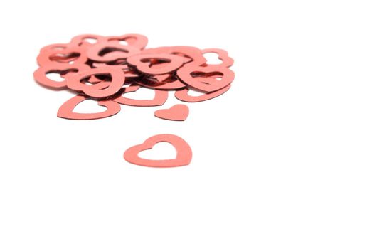 Small red decorative hearts, scattered on a white surface