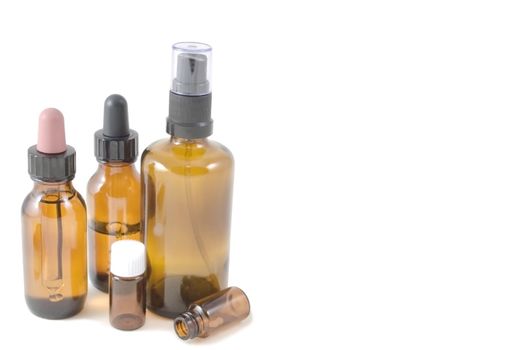 Selection of amber glass bottles traditionally used in homoeopathic prescribing.  Includes dropper bottles, pill bottles and spray bottle, against white background.  Shadows visible.