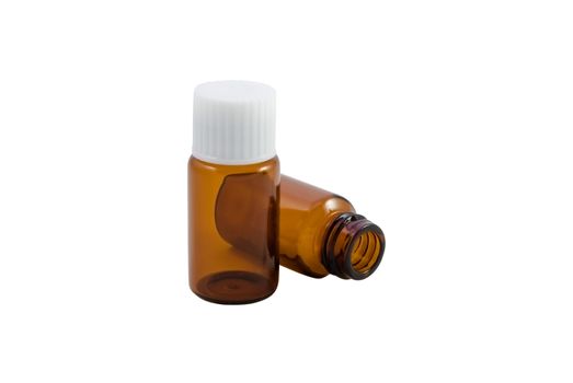 Two amber glass pill bottles, as used in homeopathy.  One upright with lid, one lying open on it's side.  Isolated with white background.