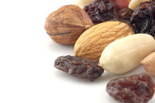 Close-up of shelled nuts and raisins mixture isolated on white with copy space to the left.  Includes hazelnut, peanut, almond, raisins.