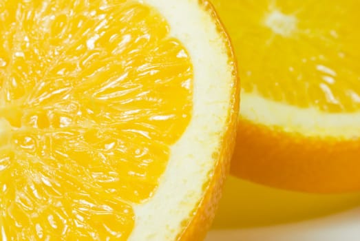 Two orange slices on a white china plate, shot in close up (macro).  Shadows visible.