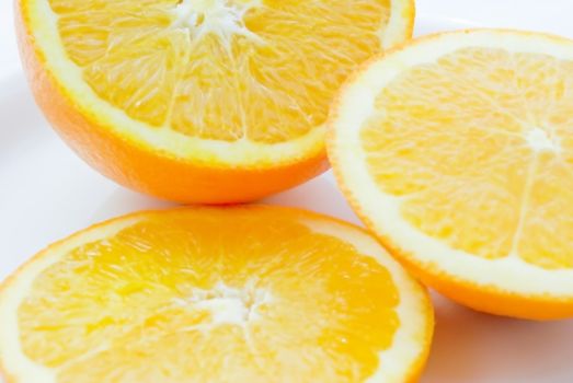 Orange cut into three parts on a white plate, white background.