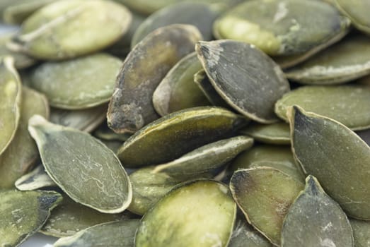 Close-up shot of numerous organic pumpkin seeds in their raw state.