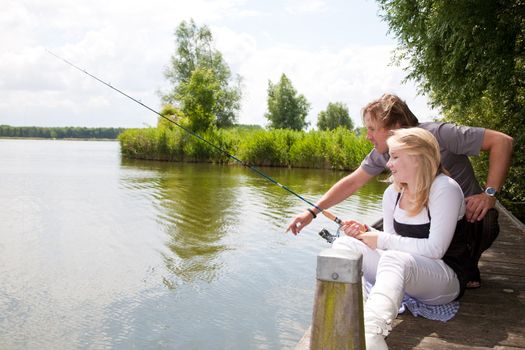 Father is teaching his daughter how to catch a fish